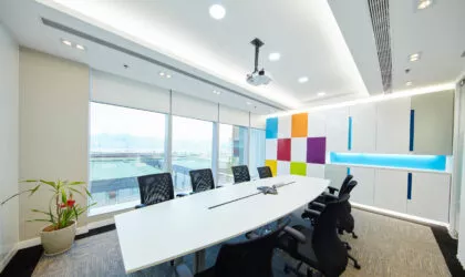 A boardroom without people, with white walls and large windows looking out to mountains in the distance