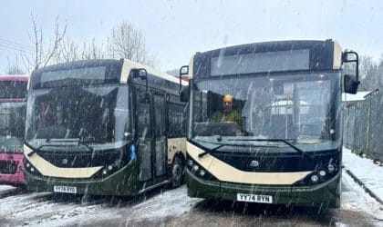 Two Alexander Dennis Enviro200 buses stand side by side in the falling snow.
